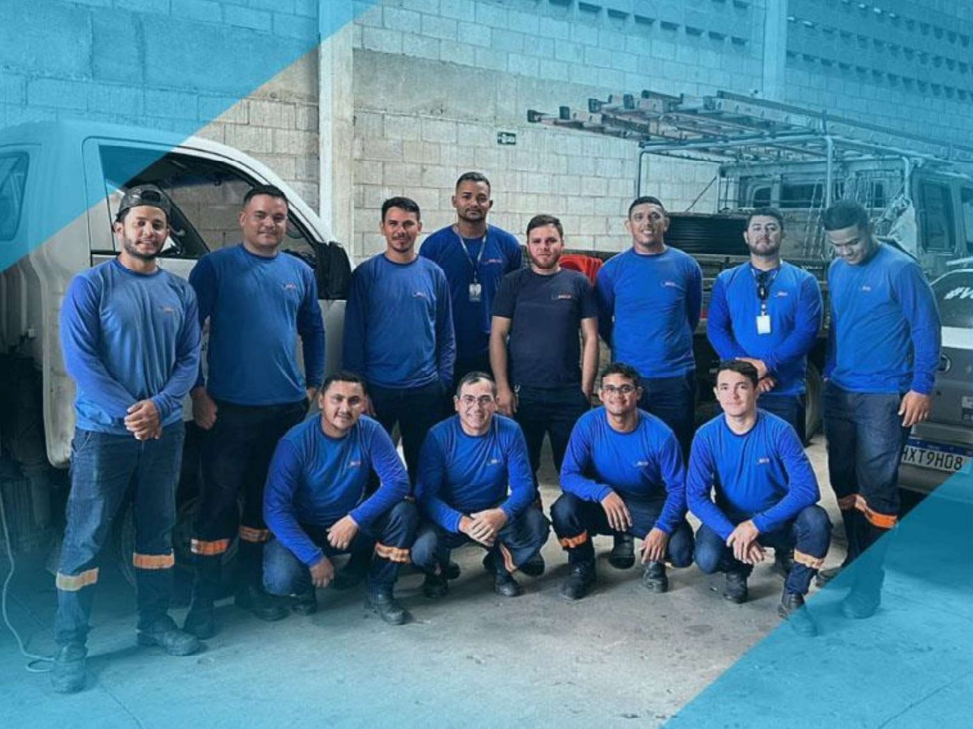Equipe técnica da MC Telecom reunida no galpão, de uniforme azul