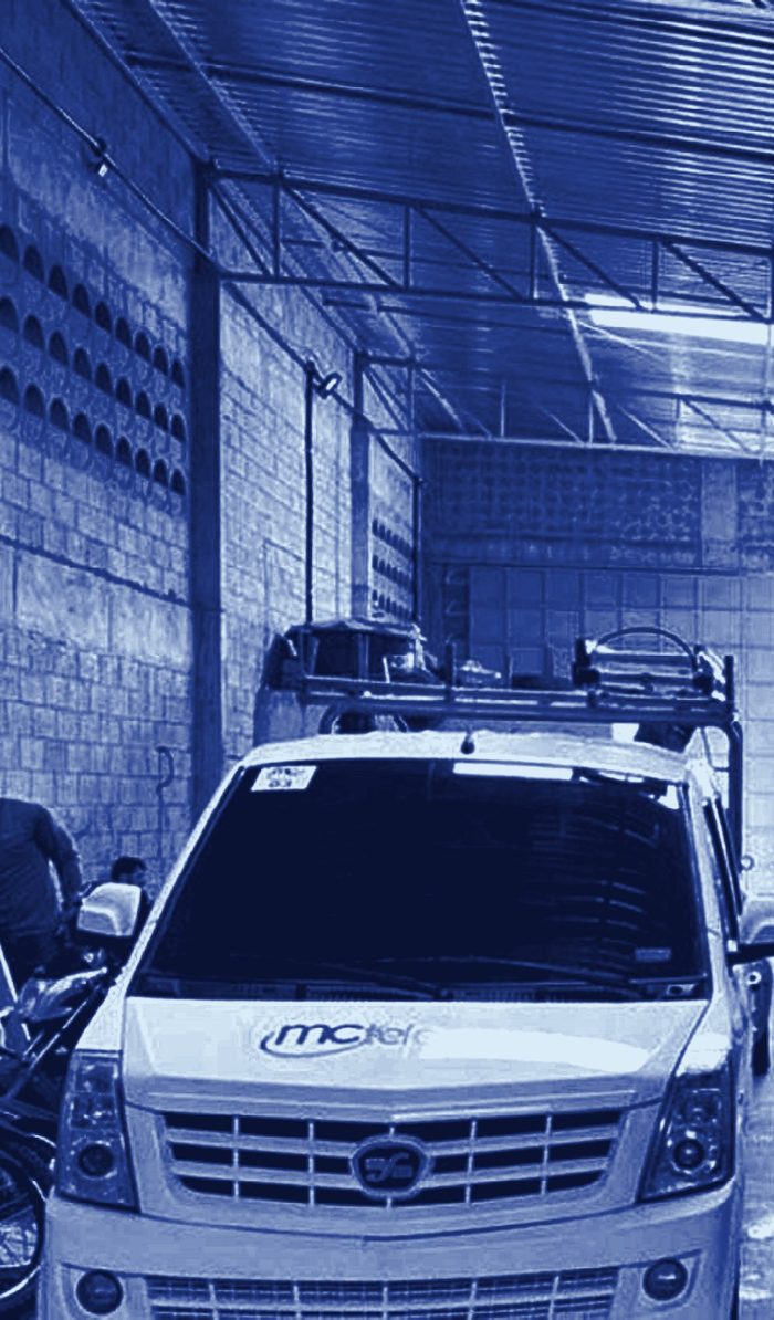 Veículo utilitário da MC Telecom com escadas no teto, estacionado no galpão